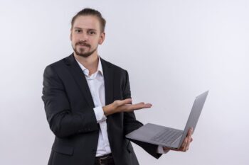 handsome business man wearing suit holding laptop computer presenting with arm hand looking confident standing white background